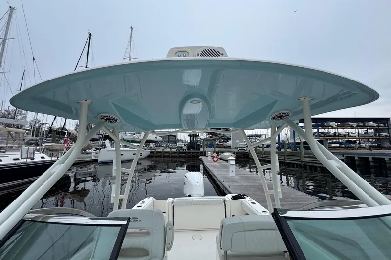 Slide: The Image of 2024 Cobia 240 Dual Console boat docked at marina, showcasing spacious seating and sleek design. - 2