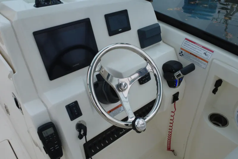 Slide: The Image of 2024 Cobia 240 Dual Console boat dashboard with steering wheel and navigation controls. - 24
