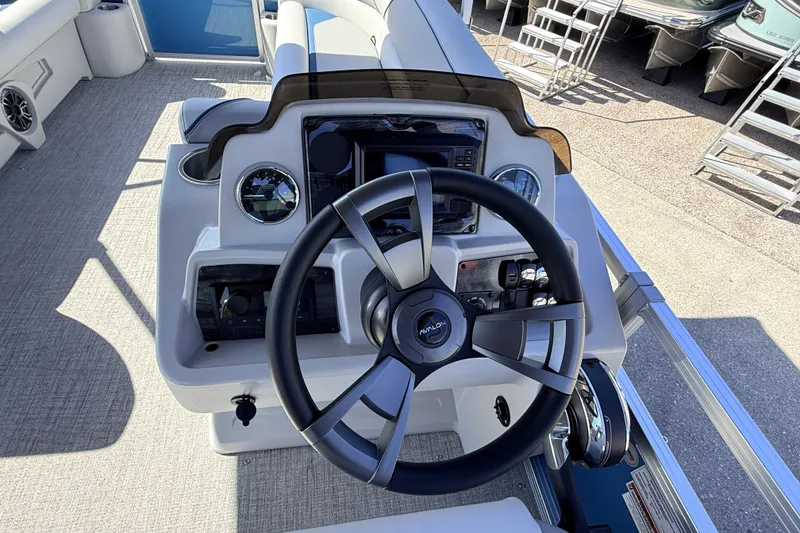 Slide: The Image of 2026 Avalon 2385 Venture 85 Quad Lounger boat helm with modern controls and steering wheel. - 23