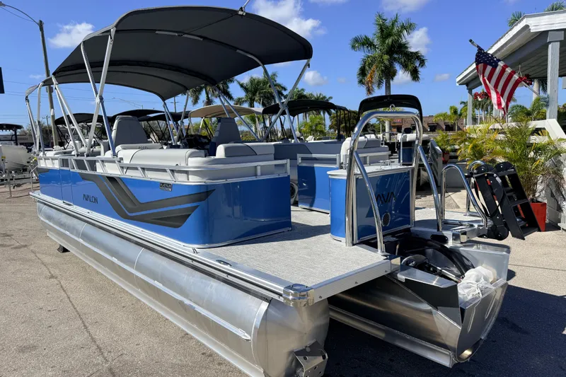 Slide: The Image of 2026 Avalon 2385 Venture 85 Quad Lounger Tri Toon boat, blue exterior, parked outdoors. - 8