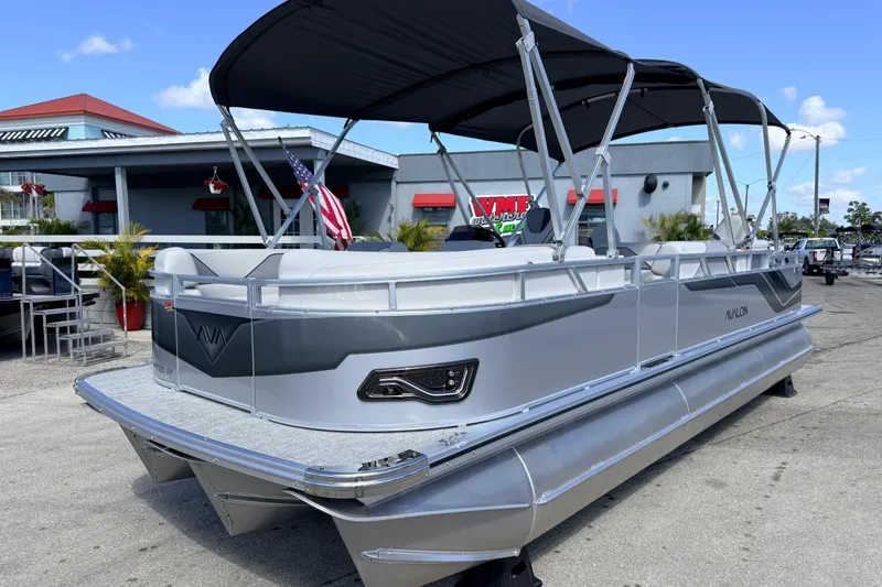 The Image of 2026 Avalon 2385 Venture 85 Tri Toon boat with canopy, parked outdoors. - 1
