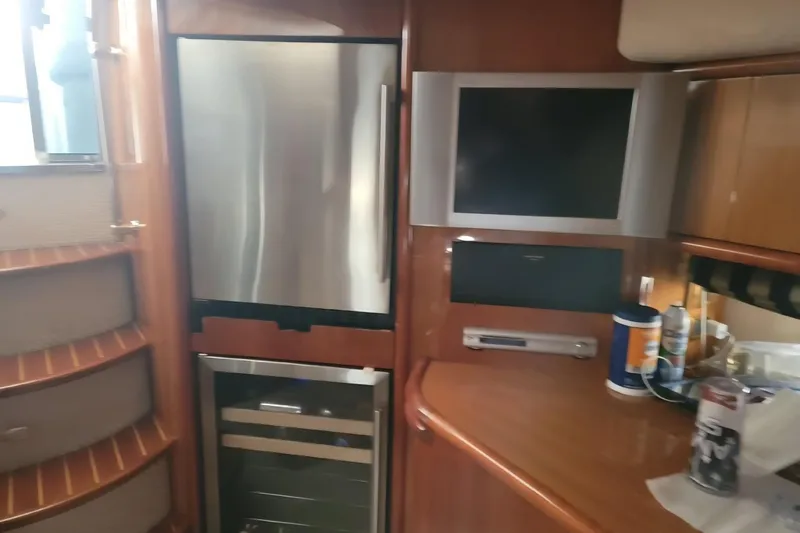 Slide: The Image of 2004 Sunseeker Predator 56 yacht interior with fridge, TV, and wooden cabinetry. - 16