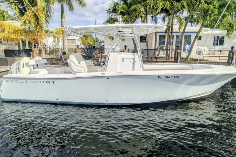 The Image of 2016 Southport 272 TE boat docked near palm trees and waterfront home. - 0