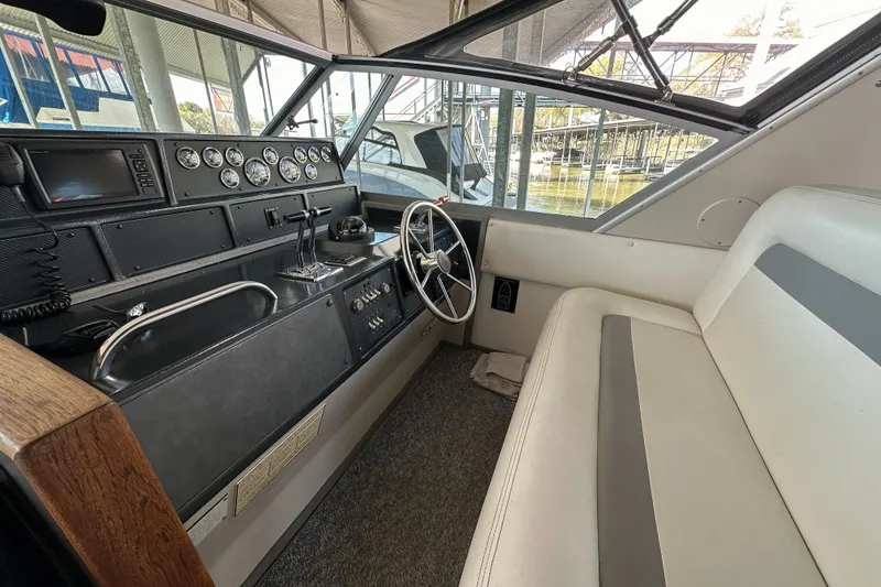 Slide: The Image of 1986 Sea Ray 390 Express Cruiser helm with gauges, steering wheel, and seating. - 23
