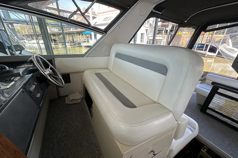 Slide: The Image of 1986 Sea Ray 390 Express Cruiser helm with white seating and steering wheel. - 24