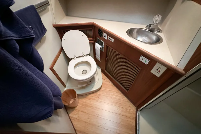 Slide: The Image of 1986 Sea Ray 390 Express Cruiser bathroom with toilet, sink, and wooden cabinetry. - 45