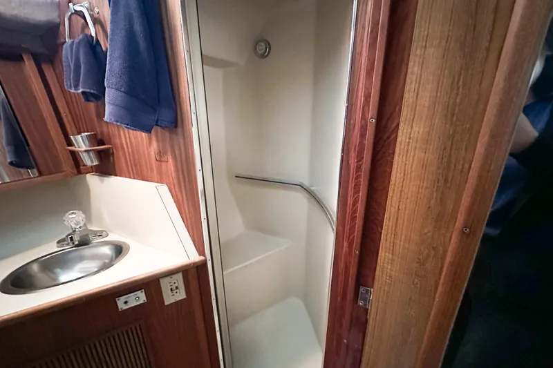 Slide: The Image of 1986 Sea Ray 390 Express Cruiser bathroom with sink, shower, and wooden cabinetry. - 46