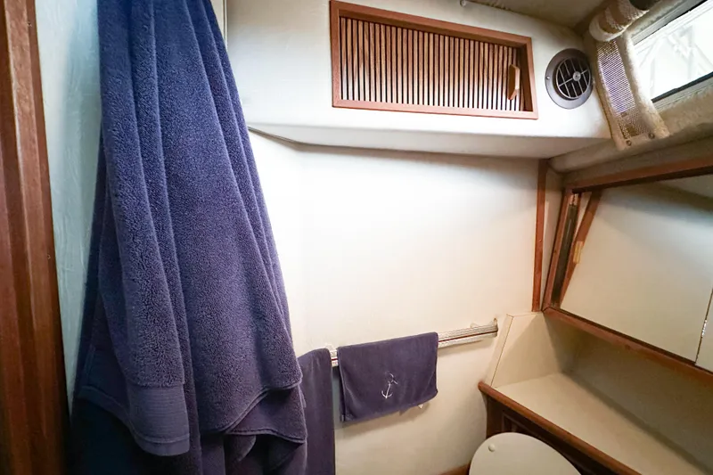 Slide: The Image of Interior of 1986 Sea Ray 390 Express Cruiser bathroom with towels and storage. - 48