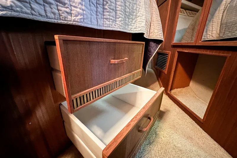 Slide: The Image of 1986 Sea Ray 390 Express Cruiser interior with open wooden drawers and carpeted floor. - 62