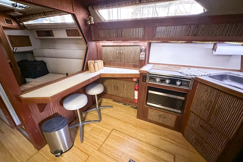 Slide: The Image of 1986 Sea Ray 390 Express Cruiser interior with kitchen, seating, and wooden cabinetry. - 65