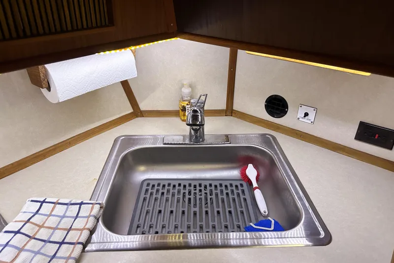 Slide: The Image of 1986 Sea Ray 390 Express Cruiser kitchen sink with cleaning supplies and paper towel holder. - 66