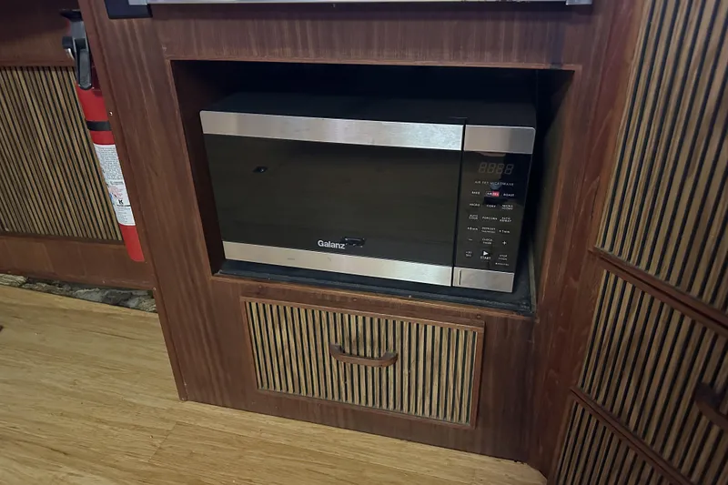 Slide: The Image of Microwave in 1986 Sea Ray 390 Express Cruiser's wooden interior kitchen area. - 68