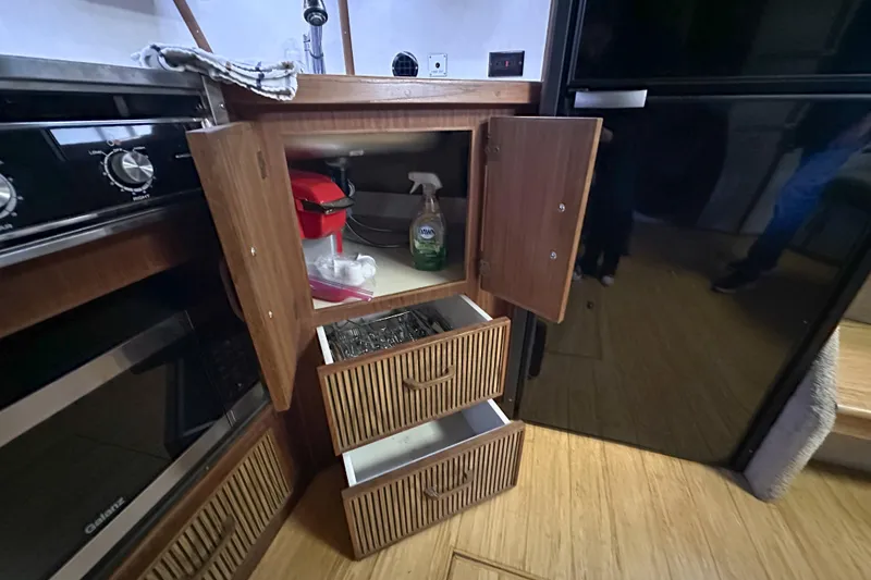 Slide: The Image of 1986 Sea Ray 390 Express Cruiser kitchen with open cabinets and drawers. - 69