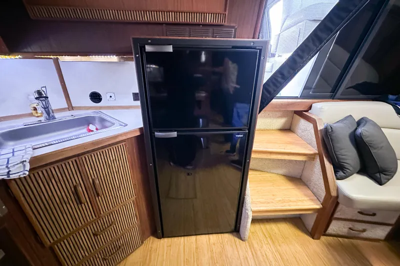 Slide: The Image of 1986 Sea Ray 390 Express Cruiser interior with kitchen sink, fridge, and seating area. - 70