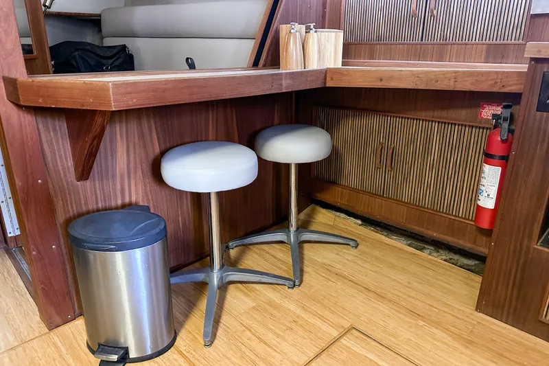 Slide: The Image of Interior of 1986 Sea Ray 390 Express Cruiser with stools, trash can, and fire extinguisher. - 74