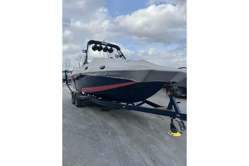 Slide: The Image of 2021 Axis A24 boat on trailer with cover, parked outdoors under cloudy sky. - 2