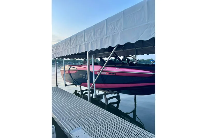 Slide: The Image of 2021 Axis A24 boat in pink and black, docked under a canopy on a calm lake. - 3