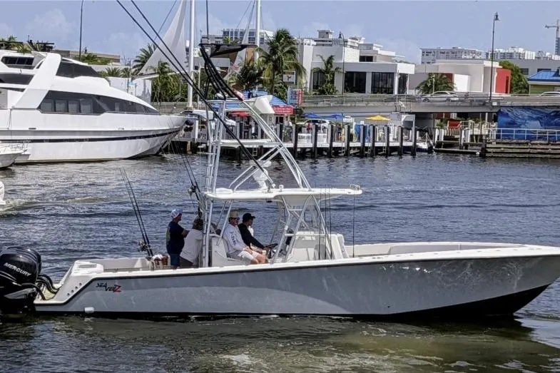 The Image of 2017 SeaVee 390Z boat cruising in a marina with fishing gear and passengers. - 1