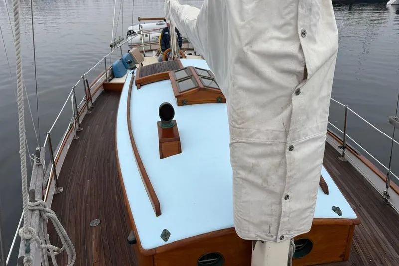 Slide: The Image of Vintage 1965 sailboat deck with wooden accents and covered mast, docked on calm water. - 14