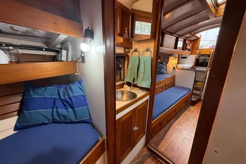 Slide: The Image of Vintage 1965 boat interior with wooden bunks, blue cushions, and compact sink area. - 23