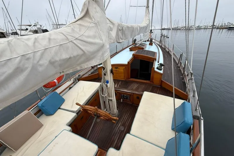 Slide: The Image of Vintage 1965 sailboat with wooden deck and cushioned seating, docked at a marina. - 9