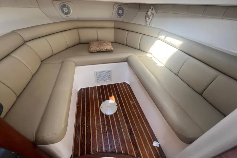 Slide: The Image of 2004 Boston Whaler 305 Conquest cabin interior with beige seating and wooden floor. - 12