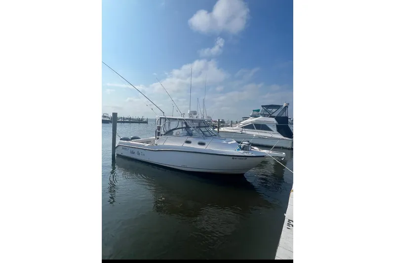 Slide: The Image of 2004 Boston Whaler 305 Conquest boat docked at marina under clear sky. - 15
