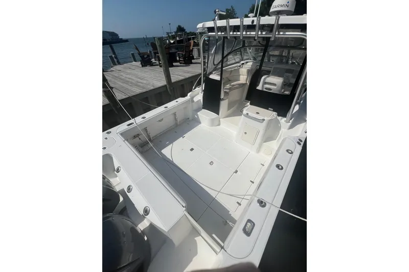 Slide: The Image of 2004 Boston Whaler 305 Conquest boat docked, showcasing spacious deck and seating area. - 18