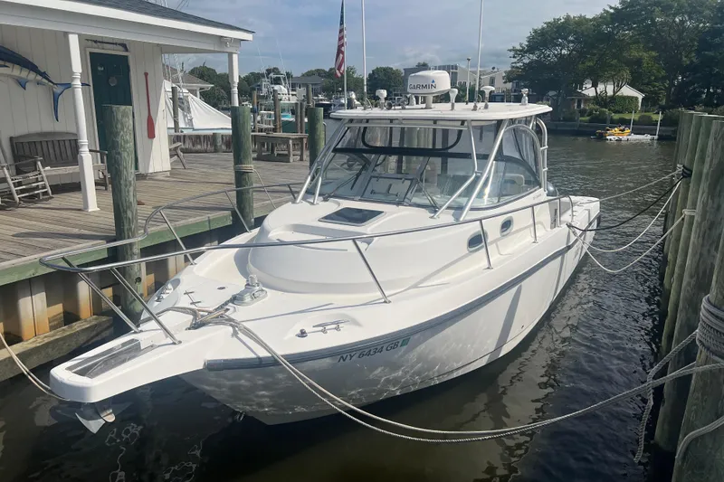 Slide: The Image of 2004 Boston Whaler 305 Conquest docked at a marina, featuring sleek design and white exterior. - 2