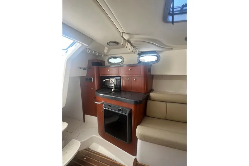 Slide: The Image of 2004 Boston Whaler 305 Conquest cabin interior with kitchenette and seating area. - 22