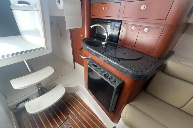 Slide: The Image of 2004 Boston Whaler 305 Conquest cabin interior with kitchenette and seating area. - 4