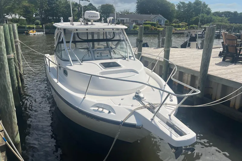Slide: The Image of 2004 Boston Whaler 305 Conquest docked at a marina, featuring a Garmin system. - 6
