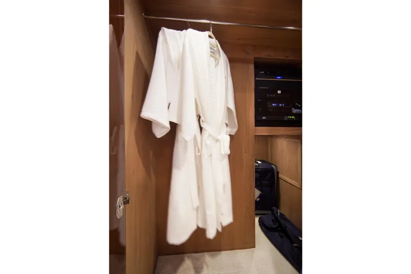 Slide: The Image of White bathrobe hanging in a wooden closet on a 2015 Hargrave 76 yacht. - 44
