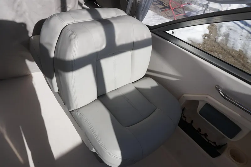 Slide: The Image of 2011 Grady-White Freedom 255 boat interior with a cushioned seat and window view. - 13