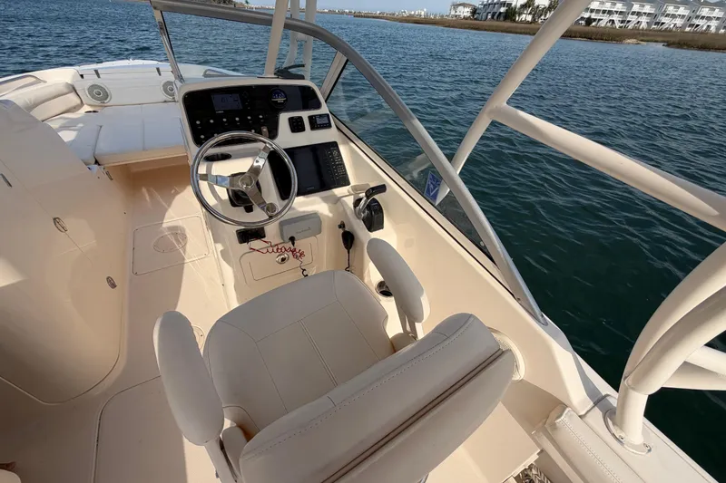 Slide: The Image of 2017 Grady-White Freedom 225 boat interior with steering wheel and seating on calm water. - 22