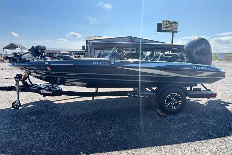 Slide: The Image of 2020 Triton 189 TrX boat on trailer, parked outdoors under clear blue sky. - 3