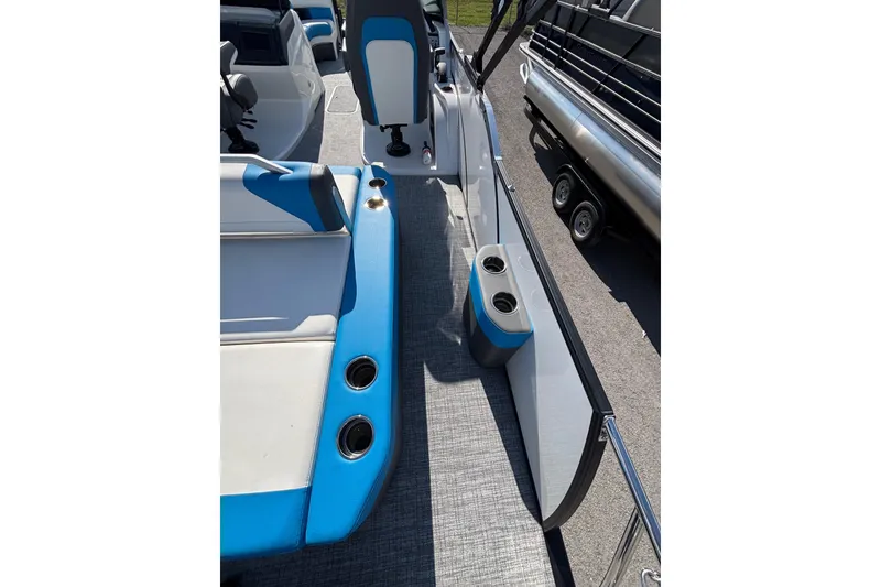 Slide: The Image of 2025 Berkshire 25UL DC STS boat interior with blue and white seating, cup holders, and carpeted floor. - 10