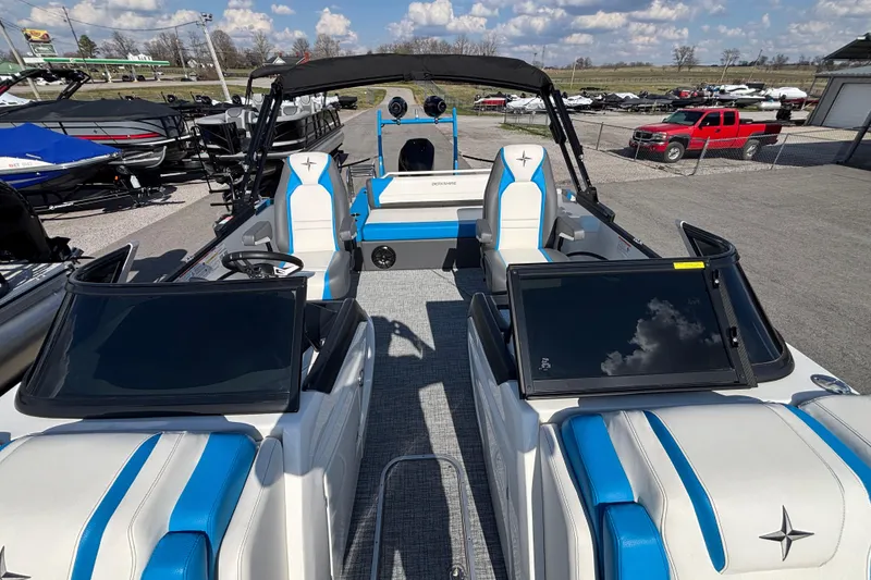 Slide: The Image of 2025 Berkshire 25UL DC STS pontoon boat with blue and white seating, parked outdoors. - 5