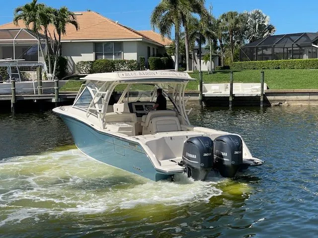 Slide: The Image of 2021 Grady-White 325 Freedom boat on water with palm trees. - 3