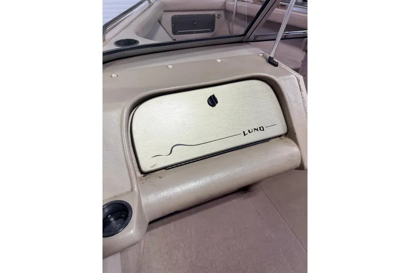 Slide: The Image of 2000 Lund 1850 Tyee Gran Sport boat interior with glove compartment and cup holder. - 17