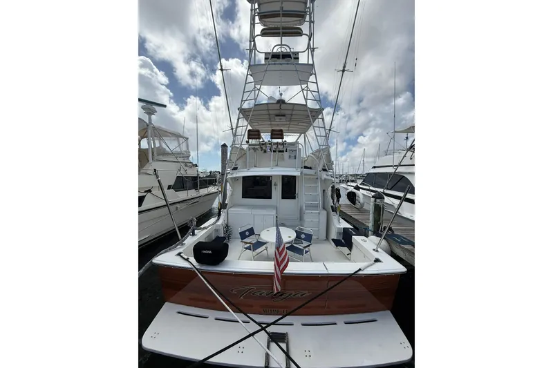 Slide: The Image of 1988 Bertram 43 Flybridge yacht docked, featuring a spacious deck and flybridge under a cloudy sky. - 11