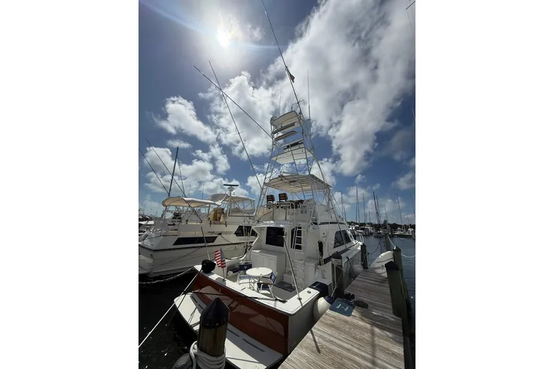 Slide: The Image of 1988 Bertram 43 Flybridge yacht docked under a sunny sky with scattered clouds. - 13