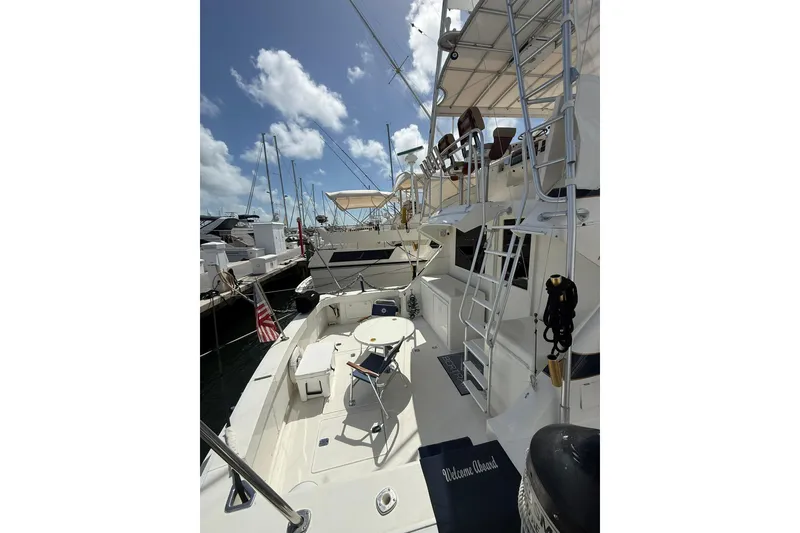 Slide: The Image of 1988 Bertram 43 Flybridge yacht docked, featuring spacious deck and seating area. - 16