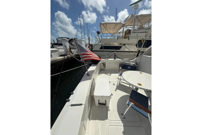 Slide: The Image of 1988 Bertram 43 Flybridge yacht deck with American flag, docked under blue sky. - 17
