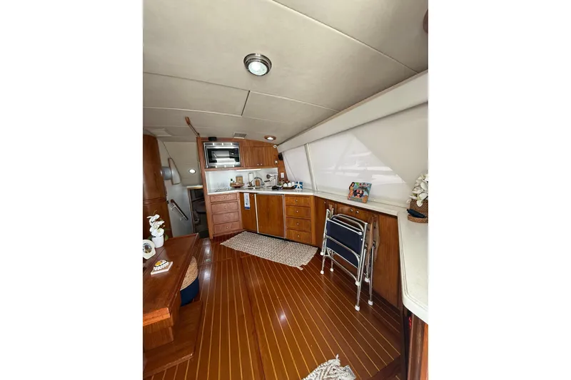 Slide: The Image of Interior of 1988 Bertram 43 Flybridge yacht with wooden flooring and compact kitchen area. - 28