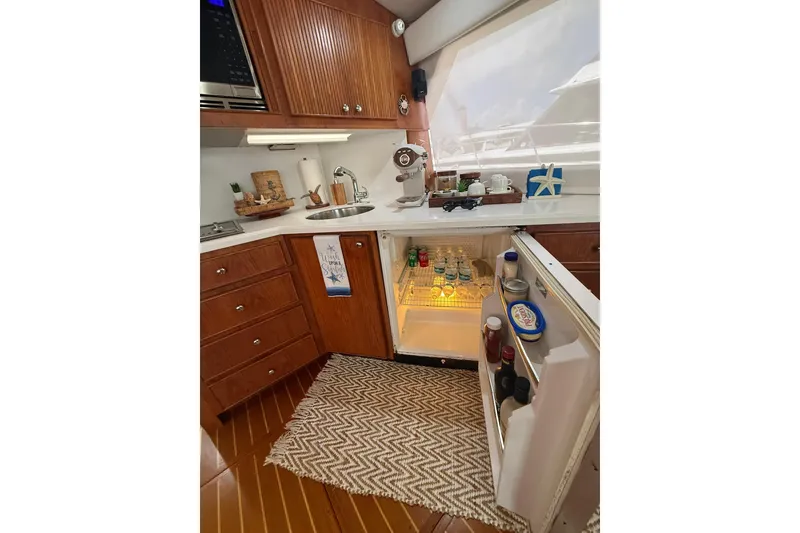 Slide: The Image of 1988 Bertram 43 Flybridge kitchen with open fridge, wooden cabinets, and countertop accessories. - 35
