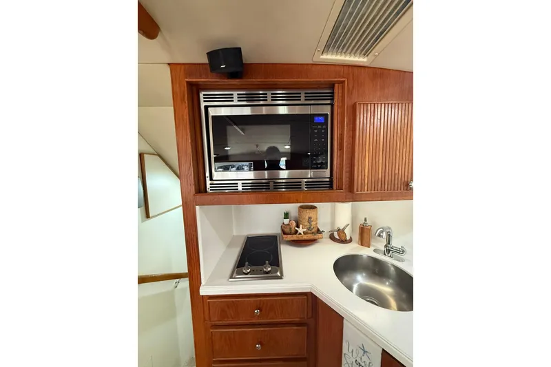 Slide: The Image of 1988 Bertram 43 Flybridge kitchen with microwave, stove, and sink in wooden cabinetry. - 36