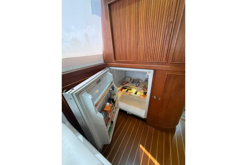 Slide: The Image of Open fridge in 1988 Bertram 43 Flybridge yacht, showcasing stocked interior and wooden cabinetry. - 37