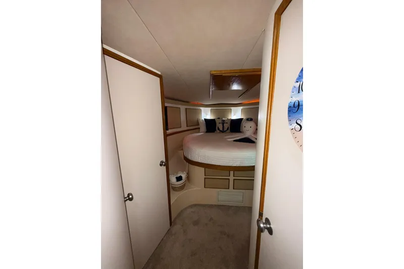 Slide: The Image of 1988 Bertram 43 Flybridge cabin interior with nautical-themed decor and cozy bedding. - 46