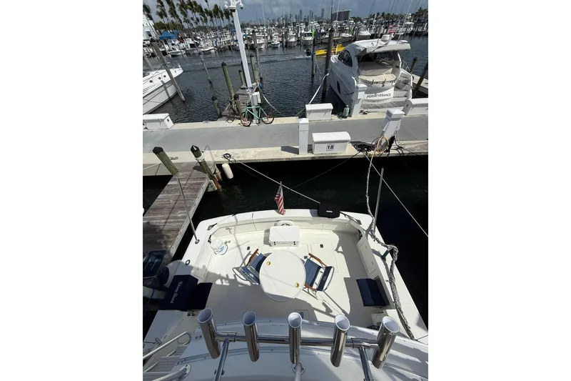 Slide: The Image of 1988 Bertram 43 Flybridge yacht docked at marina, featuring spacious deck and seating area. - 68